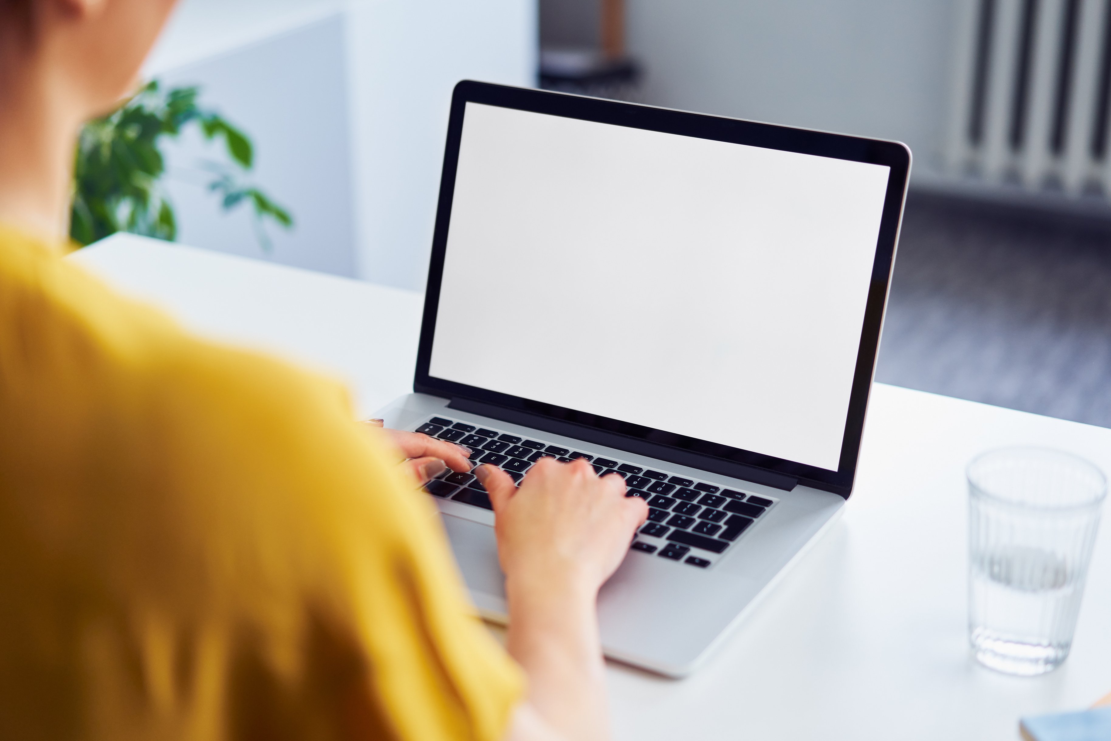 A woman is working on her computer. We are viewing the computer over her right shoulder.